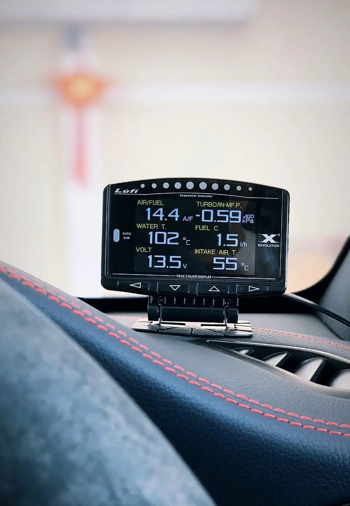 A Lufi gauge mounted on a car dashboard showing air-fuel ratio, turbo pressure, water temperature and battery voltage